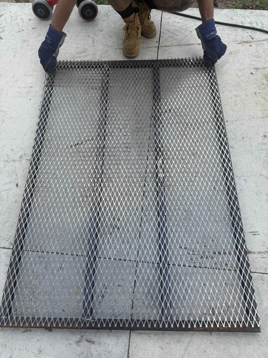 Bear Metal Fabrications welder holding a custom expanded metal security panel - mobile welding service in Highlands County FL